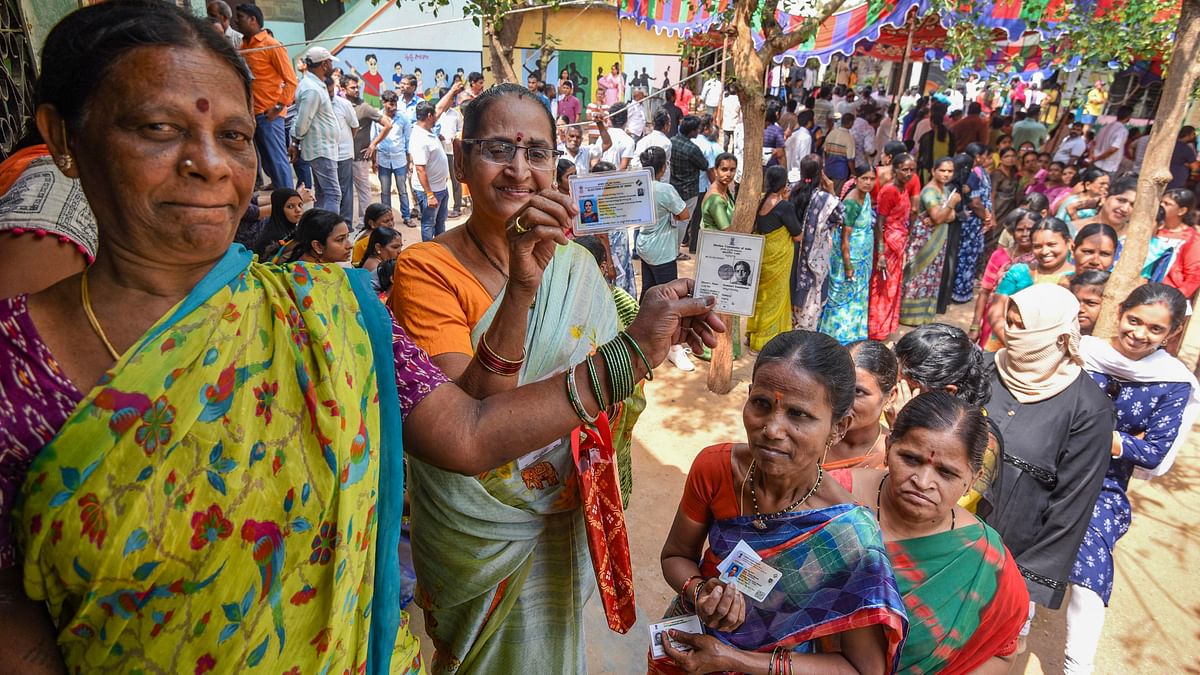 Voters show their identification cards as they stand in a queue at a polling station to cast their votes for the fourth phase of Lok Sabha elections, in Hyderabad.