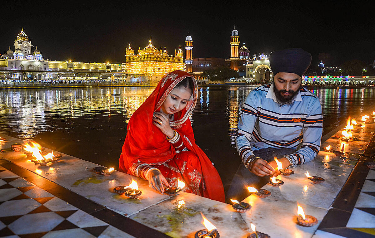 Devotees light 'diyas' at Golden Temple on the birth anniversary of the fifth Sikh Guru Arjun Dev, in Amritsar.