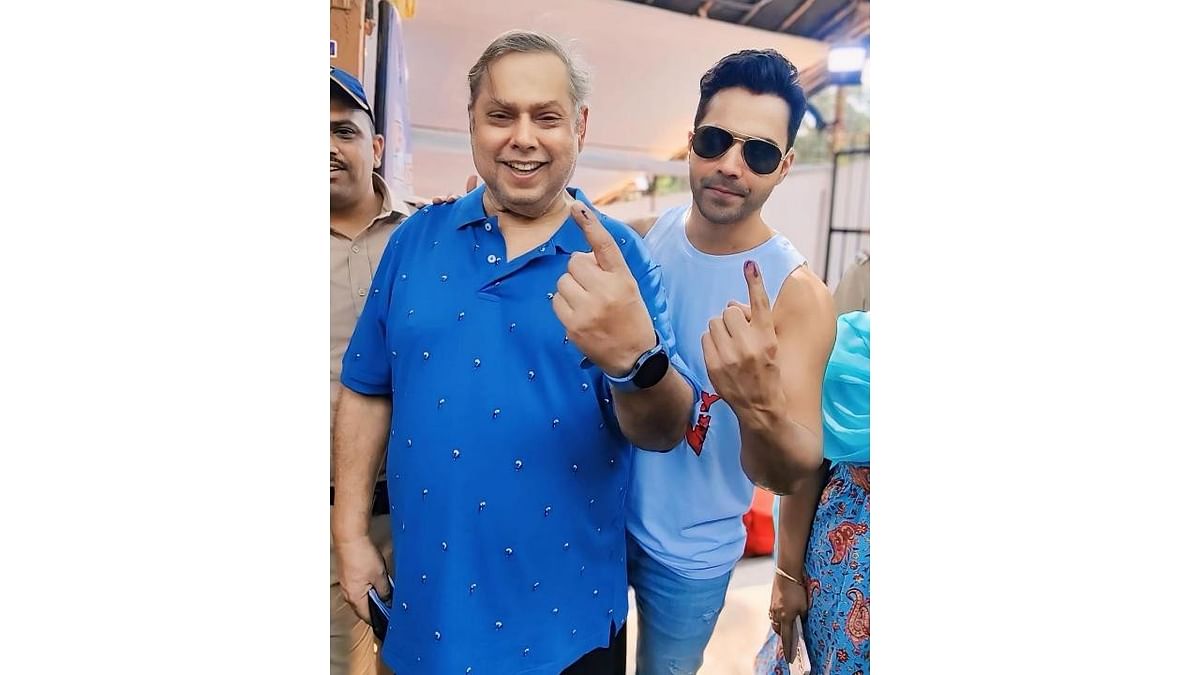 Actor Varun Dhawan and his father David Dhawan  show their ink marked fingers after casting votes, in Mumbai.