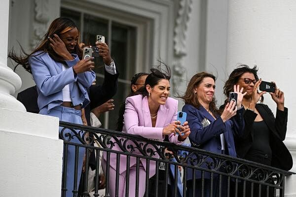 Members of the 2023 WNBA champion Las Vegas Aces react to winds caused by Marine One as U.S. President Joe Biden departs from the South Lawn of the White House in Washington.