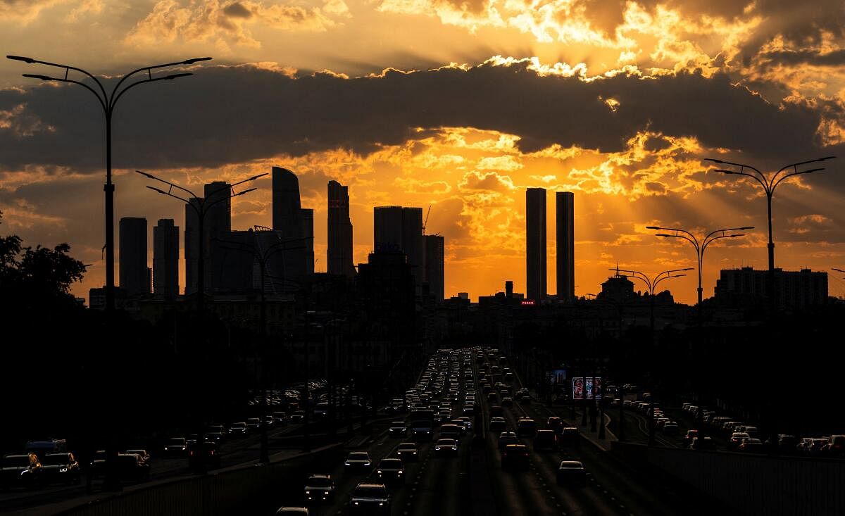 Cars drive with skyscrapers of Moskva City business district seen in the background during sunset in Moscow.