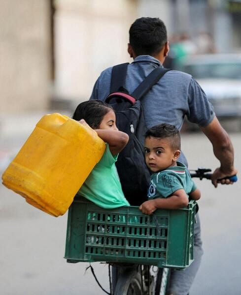 A Palestinian rides a bicycle with children along with their belongings as they flee Rafah due to an Israeli military operation, in Rafah, in the southern Gaza Strip, May 28, 2024.