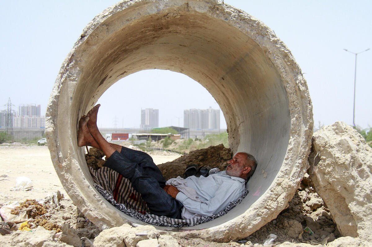 A man takes refuge inside a concrete pipe from the scorching heat on a hot summer day, in Gurugram.