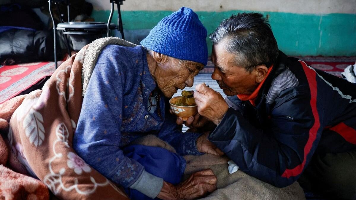 Lozbang Sherab, 75, head of the family feeds his ailing wife Pustong Lamo, 85 inside a kitchen before casting their votes, in Ladakh's remote Warshi village, home to just one family and five eligible voters, in the Ladakh region, India, May 20, 2024.