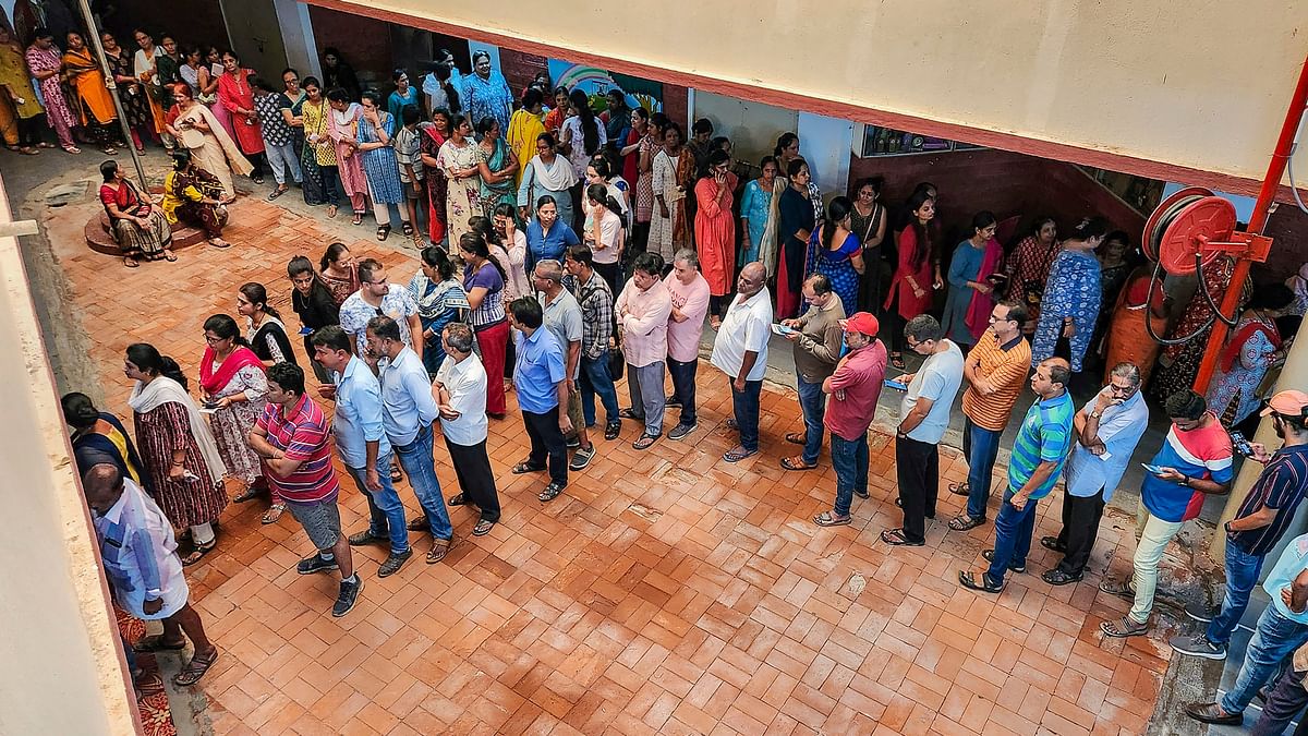 People wait in queues to cast their votes at a polling station during the third phase of Lok Sabha polls, in Hubballi.