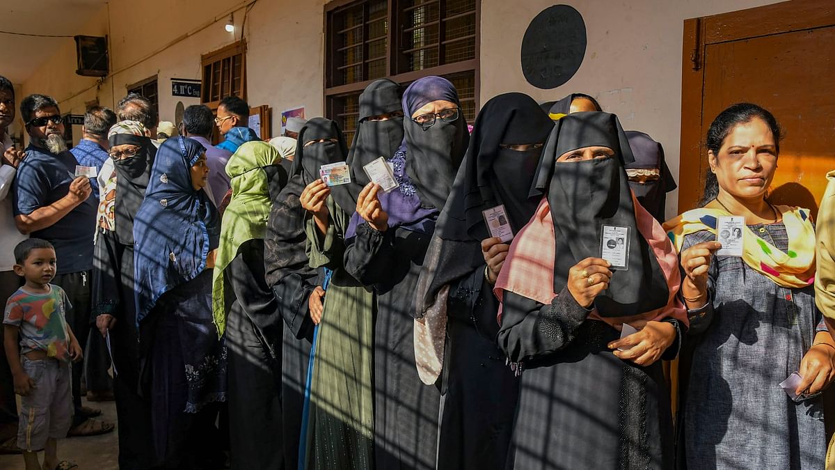 People show their ID cards as they wait in queue to cast their votes at a polling station during the third phase of Lok Sabha polls, in Karnataka.