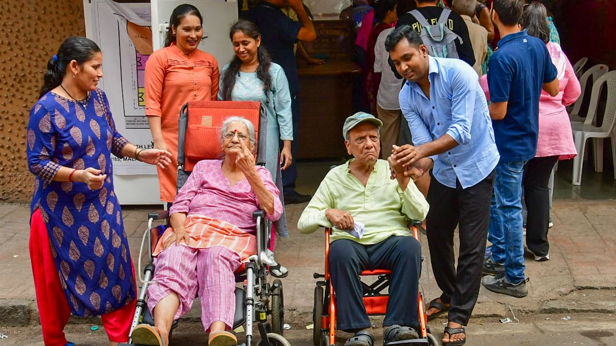 Elderly voters in wheelchairs show their inked fingers after casting votes for the fifth phase of Lok Sabha elections, in Mumbai.