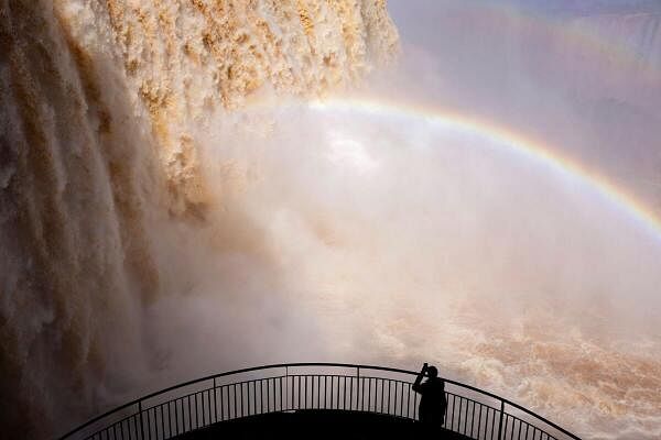 A tourist takes a picture at Iguazu Falls, which are currently at full water capacity due to the rains in southern Brazil, at Iguazu Falls.