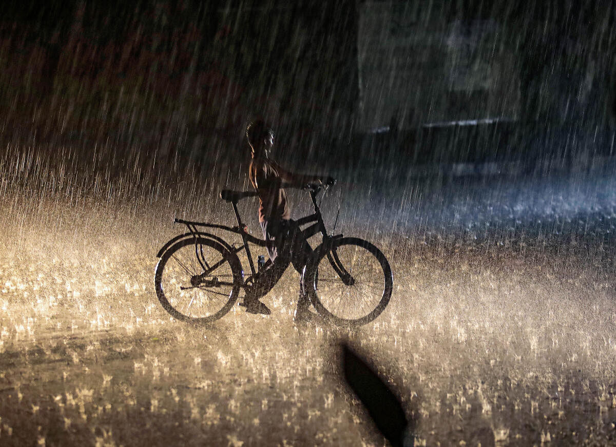 A boy moves with his cycle amid heavy rains at Ullal main road, in Bengaluru. 