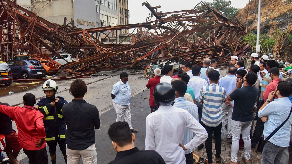 Locals gather after an under-construction metal parking tower  collapsed due to strong winds and rain at Wadala area in Mumbai.