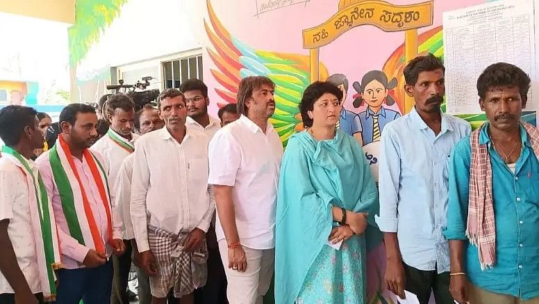 Shivamogga district in-charge minister Madhu Bangarappa stands in a queue to cast his vote with his wife at Kubatur in Sorab taluk.