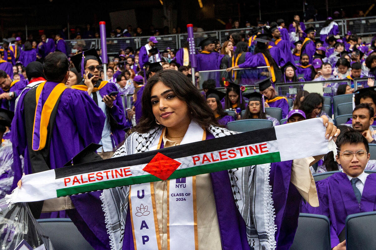 A student holds a Palestinian scarf as others attend the New York University (NYU) graduation ceremony at Yankee Stadium in the Bronx borough of New York City, May 15, 2024.