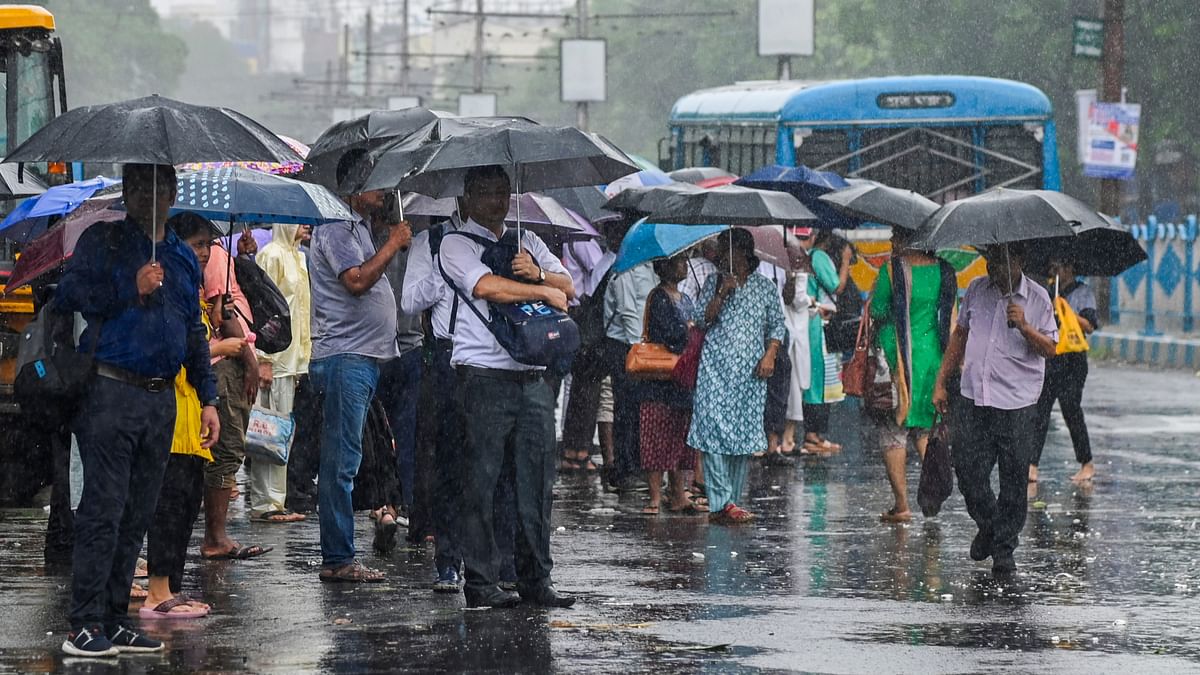 Commuters wait for buses at a stop during rain in the aftermath of Cyclone Remal's landfall, in Kolkata.