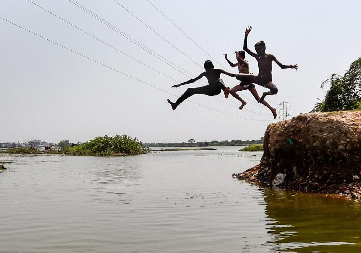 Children jump into a lake to beat the beat during summer season, in Chennai