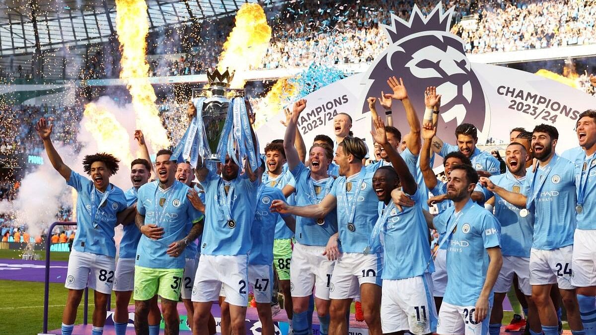 Manchester City's Kyle Walker lifts the trophy on the podium and celebrates with teammates after winning the Premier League.