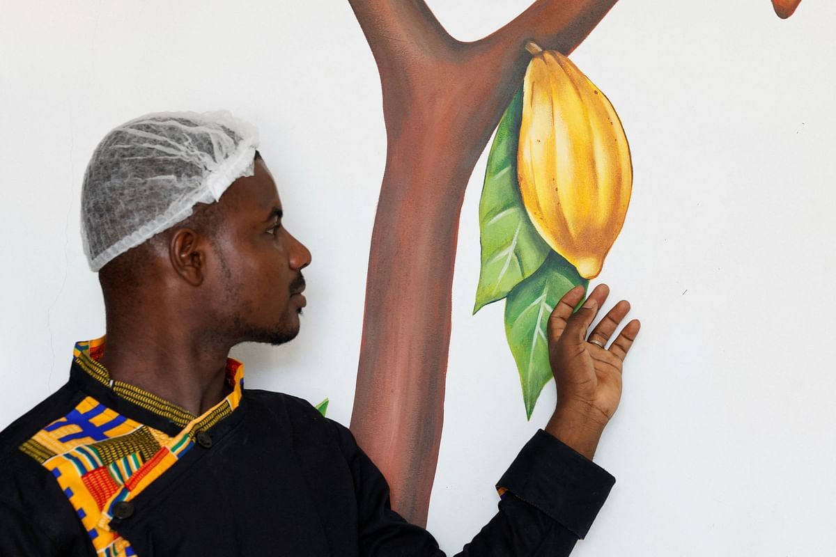 A worker stands near a painting of a cocoa pod at Chocovi, the chocolate factory of Viviane Kouame, an Ivorian chocolate artisan, in Abidjan, Ivory Coast.