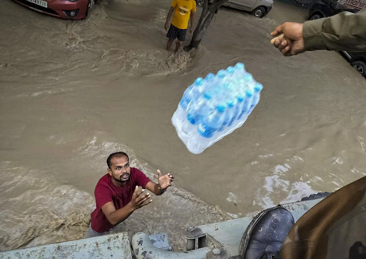Rescuers provide food to victims of flood caused by incessant rainfall in the aftermath of Cyclone 'Remal', in Imphal.