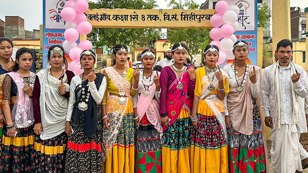Tharu tribals dressed  in traditional attire pose for a group photo after casting their vote for the fourth phase of Lok Sabha elections, in Sohni Balaigaon village located on the India-Nepal border of Bahraich.
