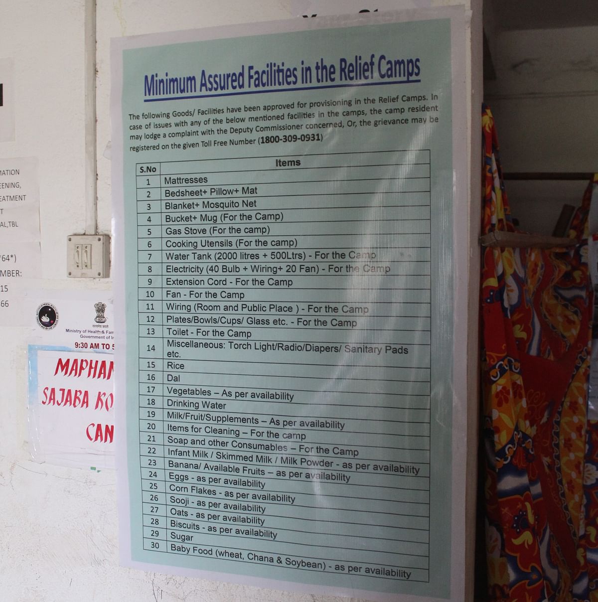A flex banner at a relief camp promising minimum assured facilities. Camp residents across the state, however, say only a few of the said facilities are provided to them now as the ethnic strife completes a full year on May 3.