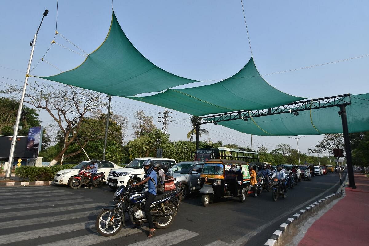 People wait for a traffic signal to open at a junction covered with tarpaulin to protect commuters from heat on a hot summer day in Bhubaneswar.