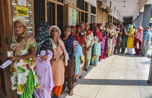 People wait in a queue to cast their votes at a polling booth during the sixth phase of Lok Sabha elections, in Haryana's Sonipat.