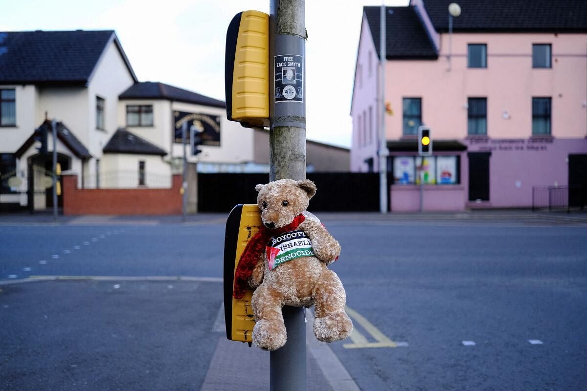 A teddy bear with a Palestinian flag sticker is tied to a traffic light in Belfast.