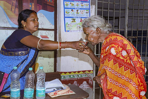 A polling agent offers water to an elderly woman during voting for the sixth phase of Lok Sabha elections, in Odisha.