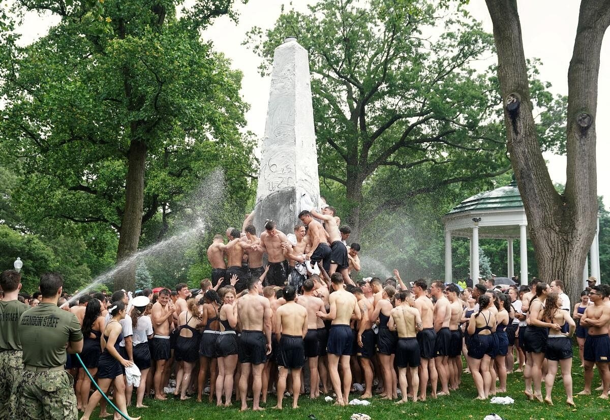 Members of U.S. Naval Academy's first year class climb the Herndon Monument, a 21-foot granite obelisk coated with a thick layer of vegetable shortening, in a ritual marking the end of their plebe year in Annapolis, Maryland, US, May 15, 2024.