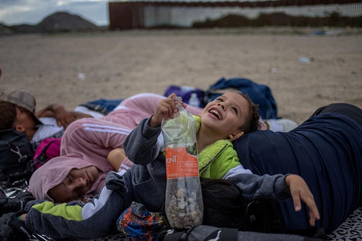 Dylan, a four year old migrant from Mexico, smiles while playing with his aunt Daniela, 24, as his parents Ivan, 22, and Rubi, 22, sleep on the left after the Rivera family crossed the Border Wall into the United States from Mexico in Ruby, Arizona, US, June 26, 2024.