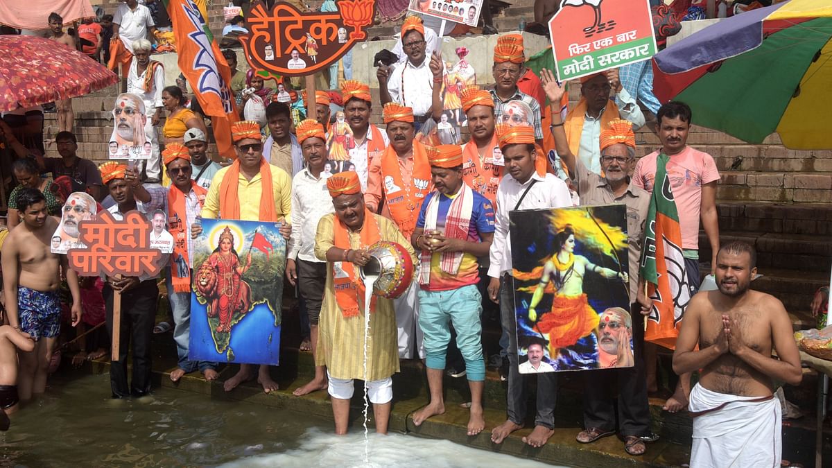 BJP supporters hold posters of Prime Minister-designate Narendra Modi as they offer milk to Ganga river, ahead of his swearing-in ceremony, at Shitala Ghat, in Varanasi.