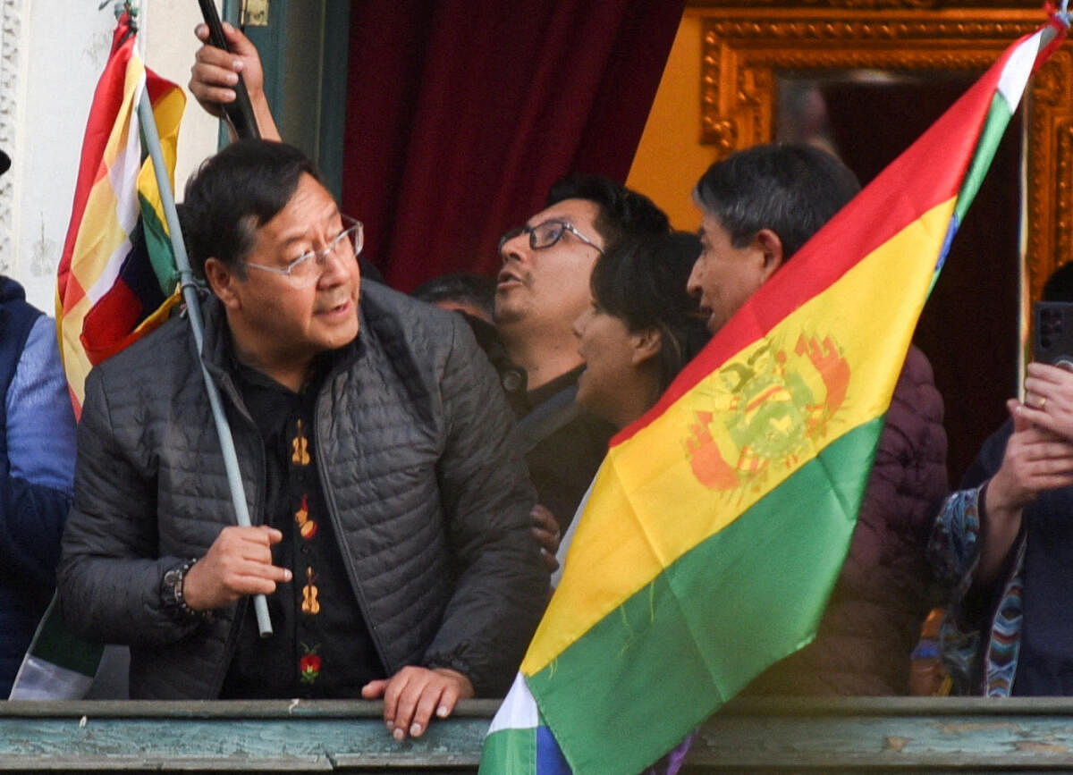 Bolivia's President Luis Arce holds a flag as he stands on a balcony after he 