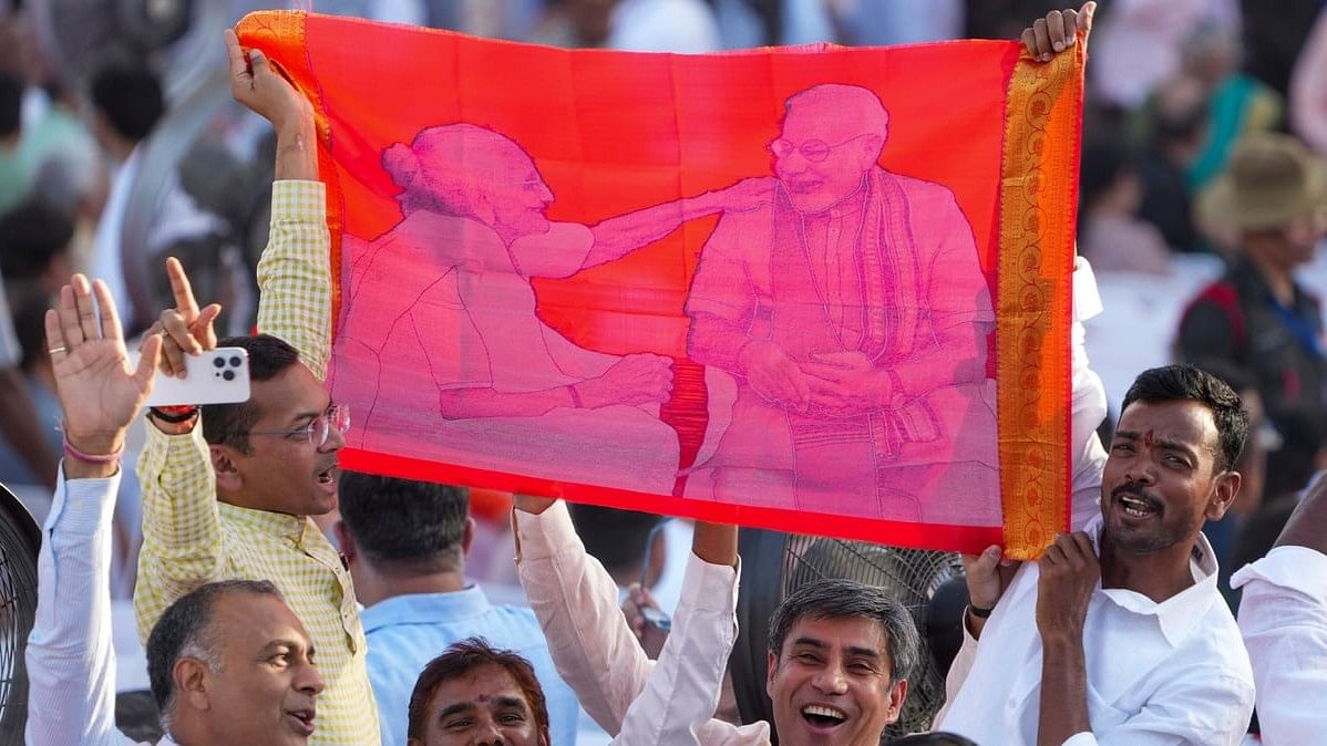 Supporters hold a banner depicting Prime Minister-designate Narendra Modi and his mother Heeraben Modi as they wait for the swearing-in-ceremony of the new Union government at the Rashtrapati Bhavan in New Delhi.