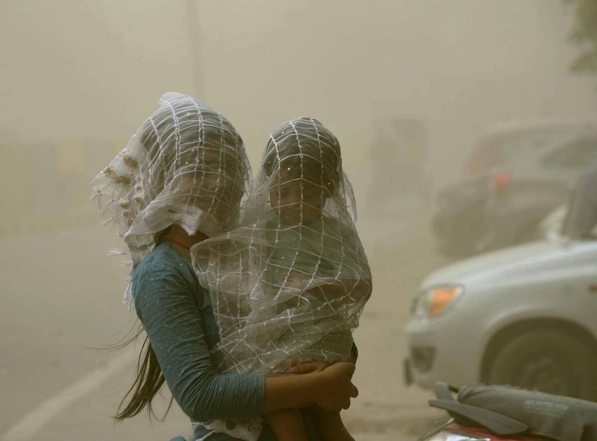 Patna: A woman covers herself and her child during a dust storm, in Patna, Thursday, June 6, 2024. 