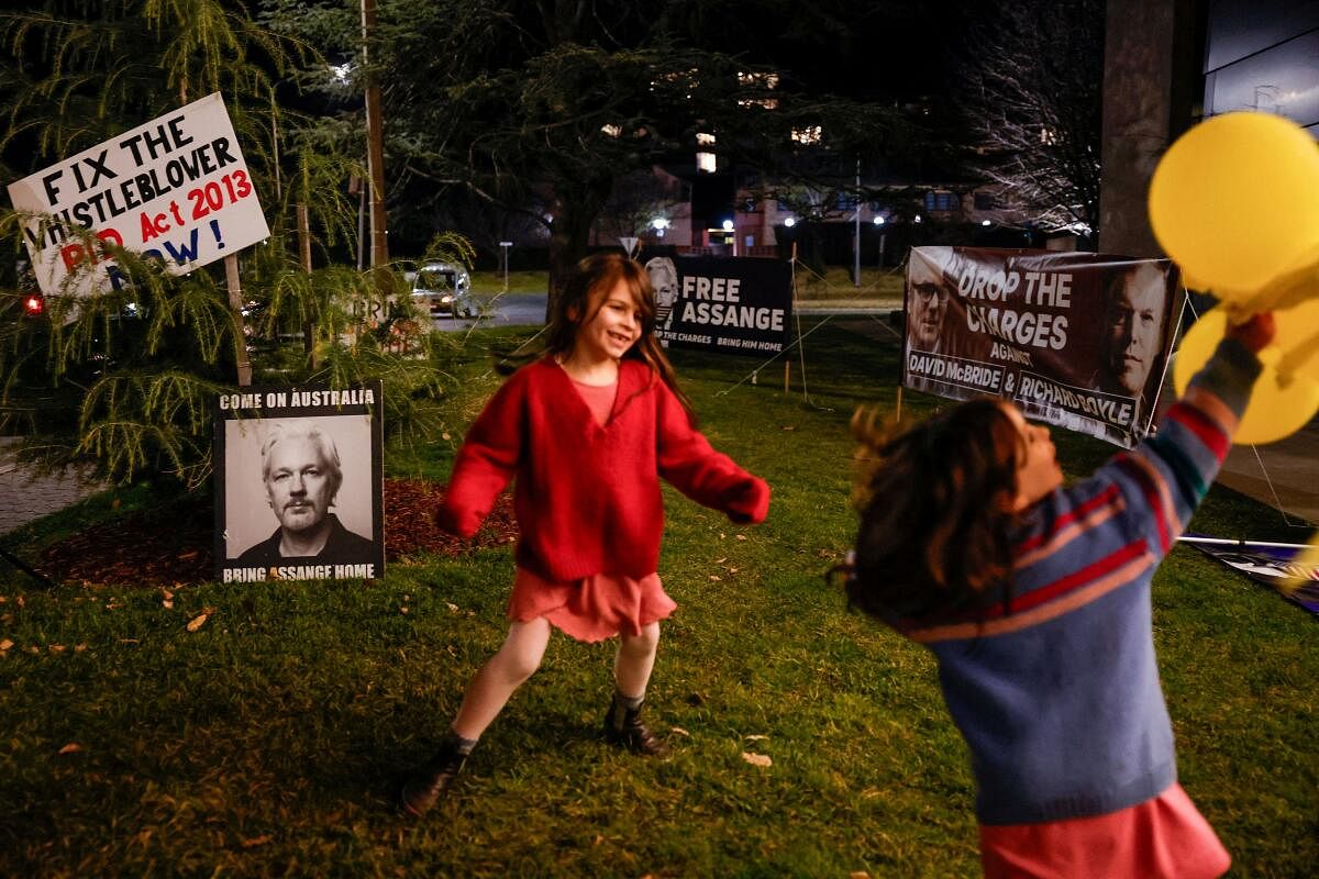 Children play next to placards and banners in support of WikiLeaks founder Julian Assange, on the day of Assange's arrival in Australia, in Canberra, Australia, June 26, 2024.