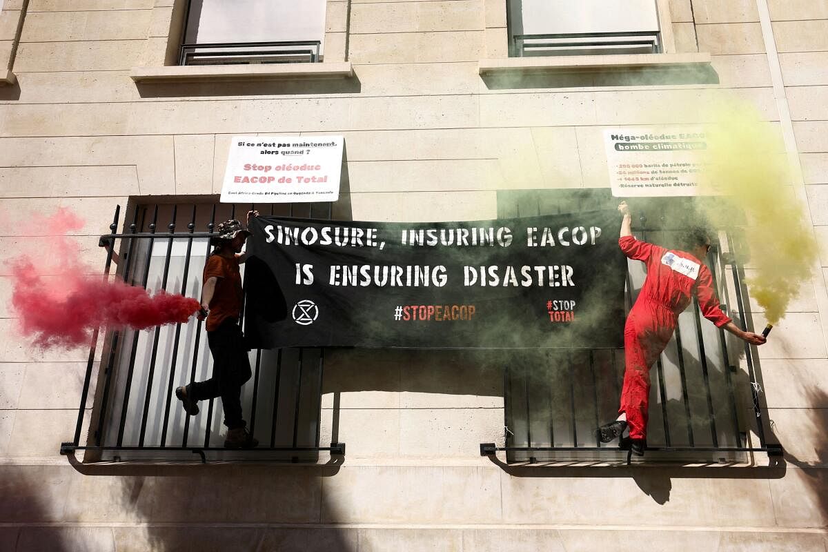 Climate activists install a banner and placards on the Chinese embassy as part of actions to protest against TotalEnergies and the East African Crude Oil Pipeline (EACOP) project, in Paris, France, June 26, 2024. The slogans read "Sinosure, Insuring EACOP is ensuring disaster" and "Stop Total’s EACOP oil pipeline".
