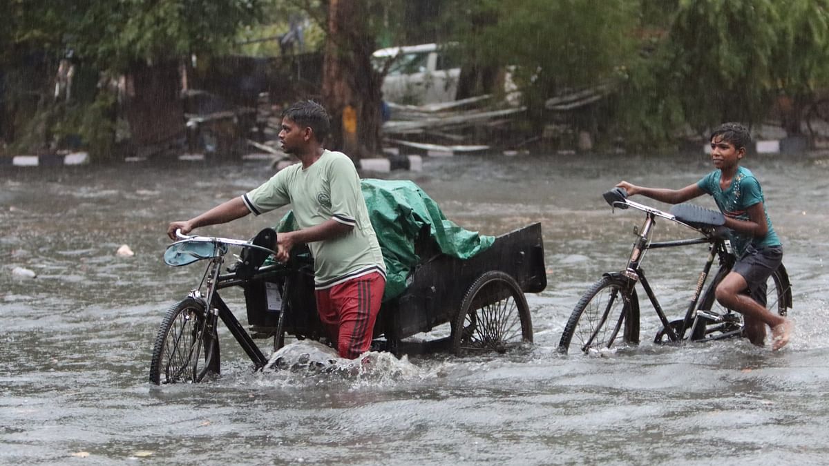 People wade through a waterlogged road amid rains, in New Delhi.