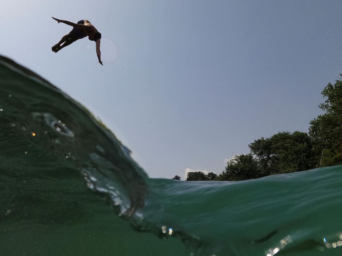 A man jumps into the Drinos river to cool off during the heat wave, near Tepelena, June 22, 2024. 