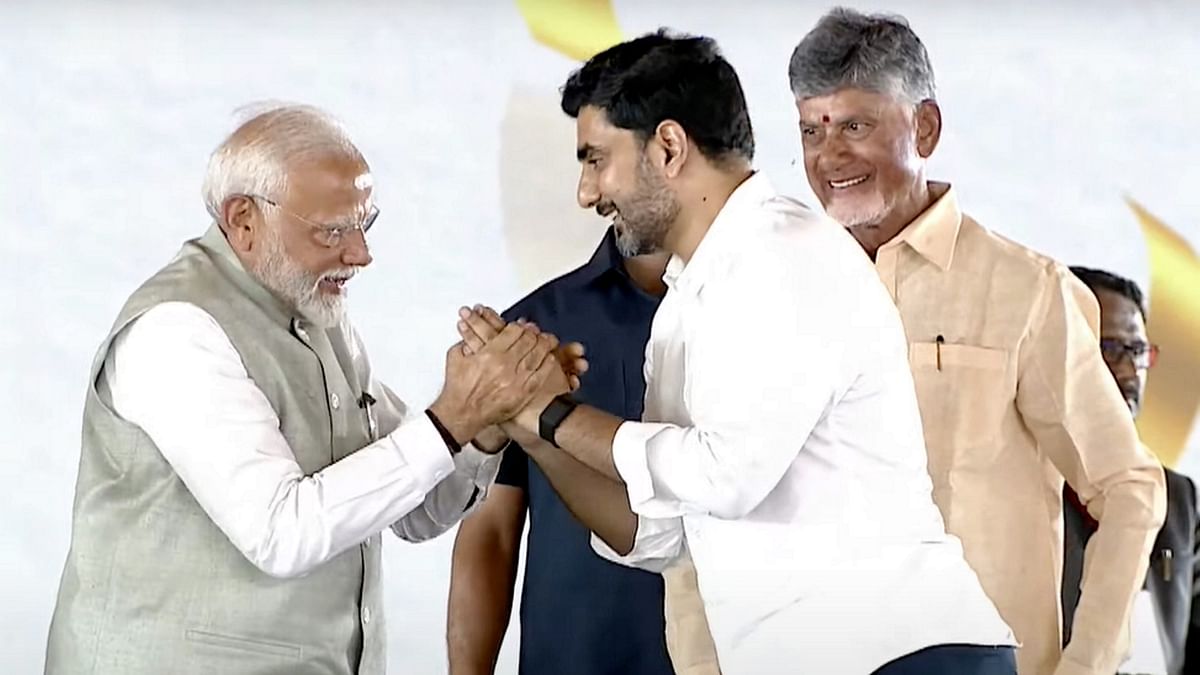 Prime Minister Narendra Modi greets Nara Lokesh as Andhra  CM Naidu looks on during the swearing-in ceremony, in Vijayawada.
