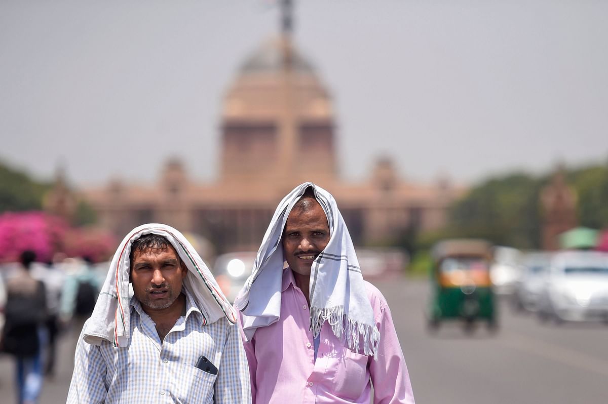 Pedestrians cover their heads to shield from the scorching sun, on a hot summer day, in New Delhi.