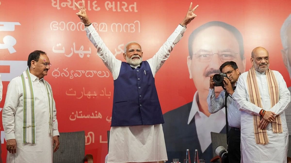 Prime Minister Narendra Modi flashes victory sign during a meeting at the party headquarters as the party leads in the Lok Sabha elections amid the counting of votes, in New Delhi.