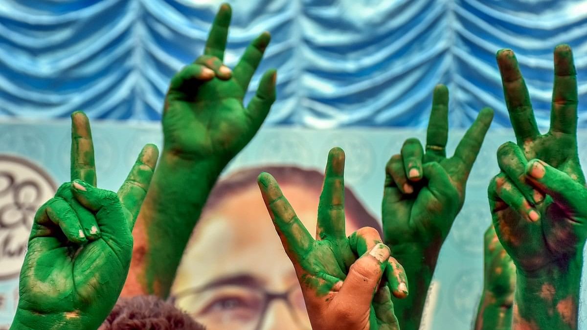 TMC supporters flash victory signs covered in green 'gulaal' as they celebrate the party's lead during counting of votes for Lok Sabha elections, in Murshidabad.