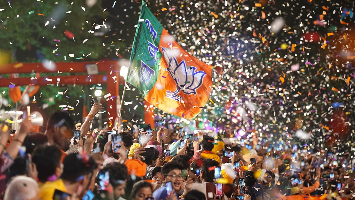 Supporters wave the party flag during the arrival of Prime Minister Narendra Modi for a meeting at BJP headquarters as the party leads in the Lok Sabha elections amid the counting of votes, in New Delhi.