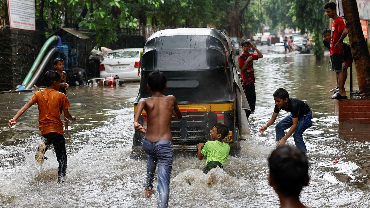 A boy clings to an auto rickshaw on a waterlogged street after heavy rains in Mumbai.