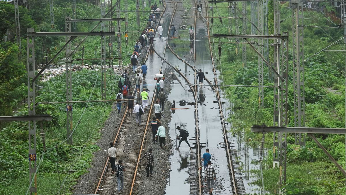 People walking through a waterlogged railway track following rains in Mumbai.