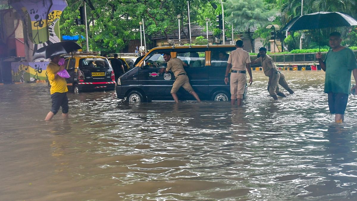 Policemen push a vehicle stuck on a waterlogged road during monsoon rain at Parel in Mumbai.