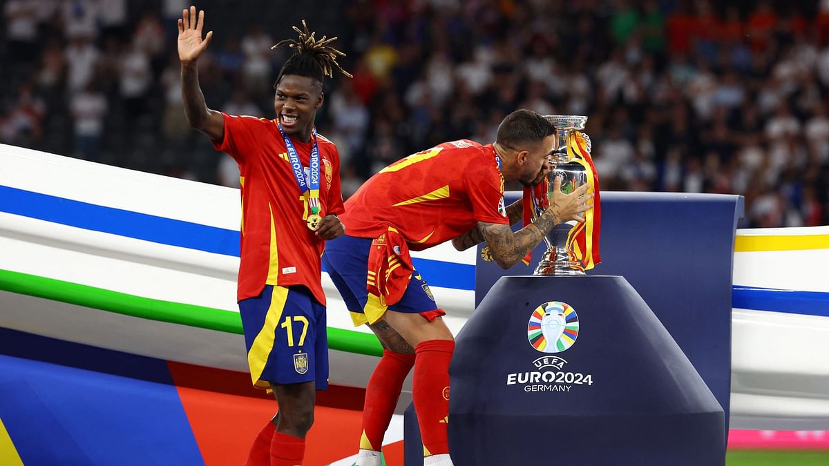 Spain's Joselu kisses the trophy as Nico Williams waves during the presentation ceremony.