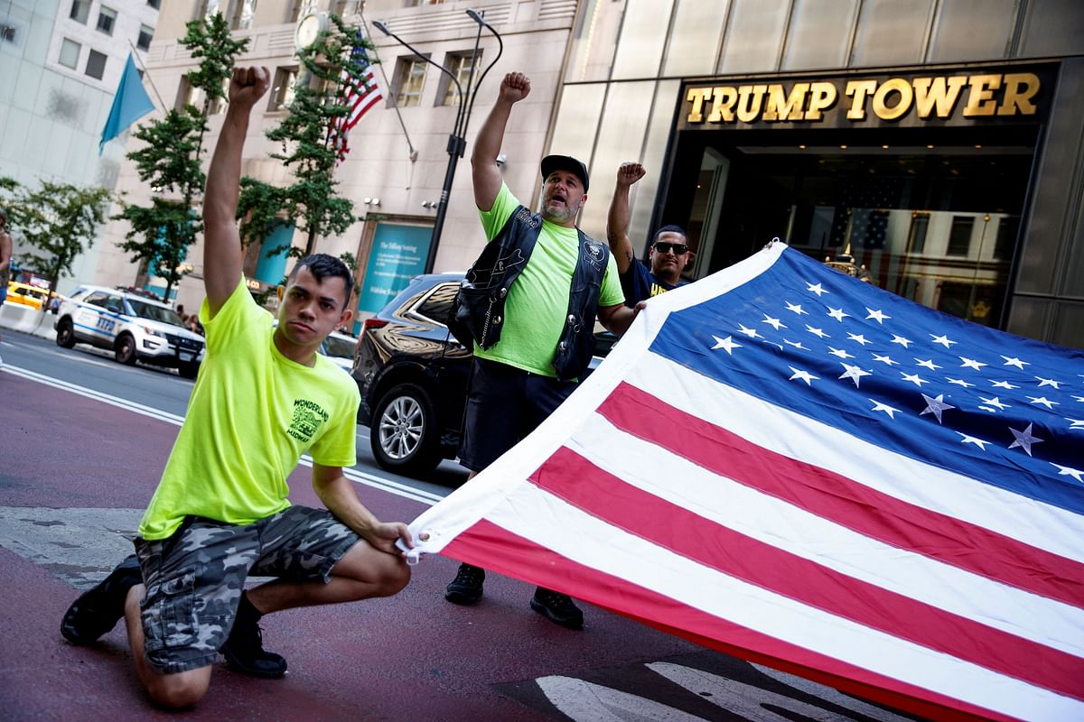 People hold a U.S. flag in fron of the Trump Tower, after U.S. President Trump was injured during a campaign rally, in New York