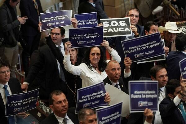 Members of Colombian congress from opposition parties hold signs that read "We are the opposition, out with corruption" during the opening of the new session of the Colombian Congress, in Bogota, Colombia.