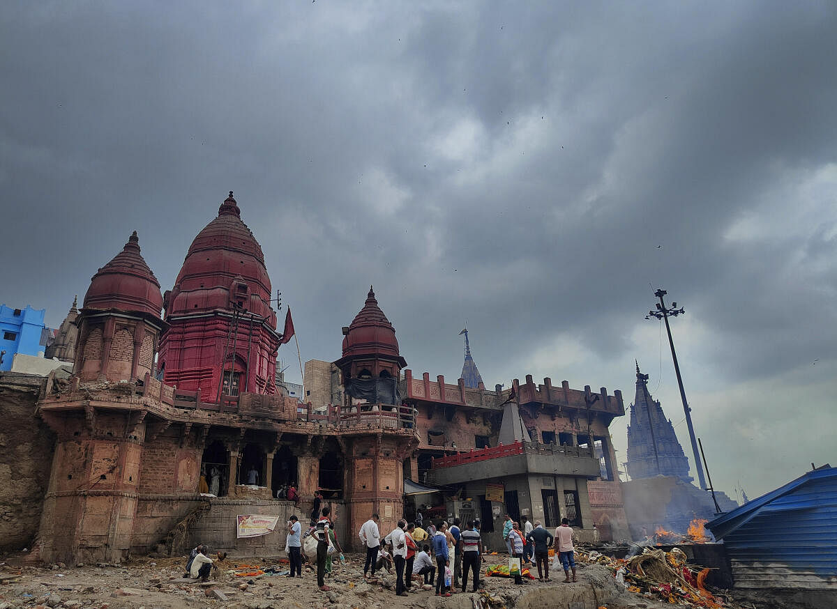 Devotees offer prayers at a temple as dark clouds hover in the sky, in Varanasi. 