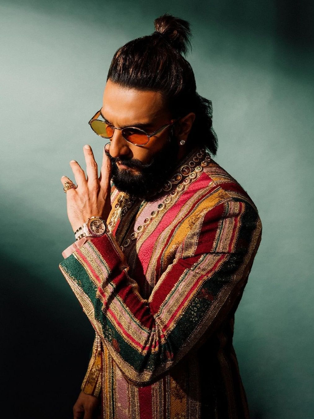 Wearing a long kurta with colorful stripes, Ranveer added extra flair to his jaw-dropping royal look with his ponytail, shiny beard, and shades. 